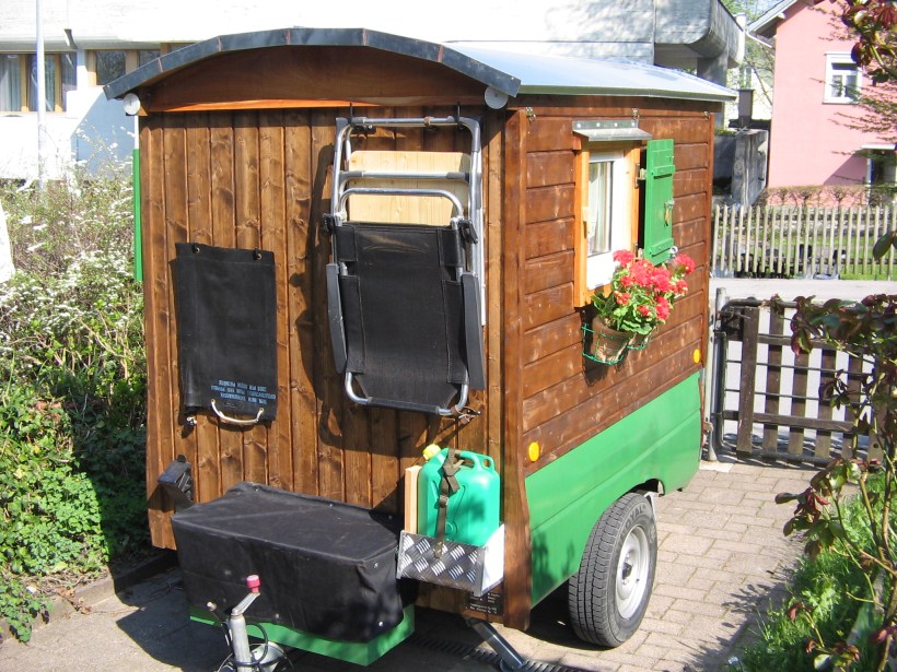 Westseite mit Aussentisch /Stuhl und Sonnenbeheiztem Wasser/Reservediesel Materialkiste Südseite mit Geranien